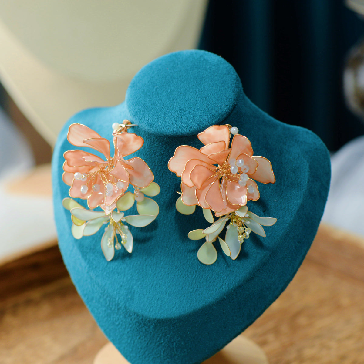 Ayaka peach resin floral earrings and hair accessory set on a teal display stand
