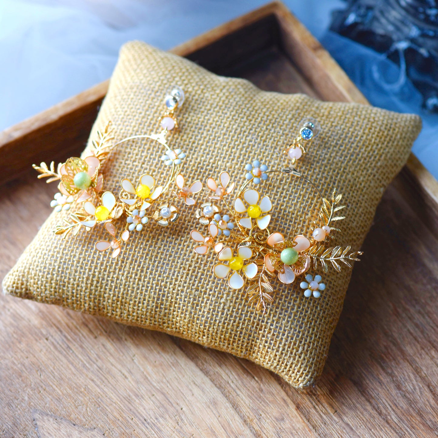 Betty yellow gold and green resin floral long drop earrings on an embroidered cushion