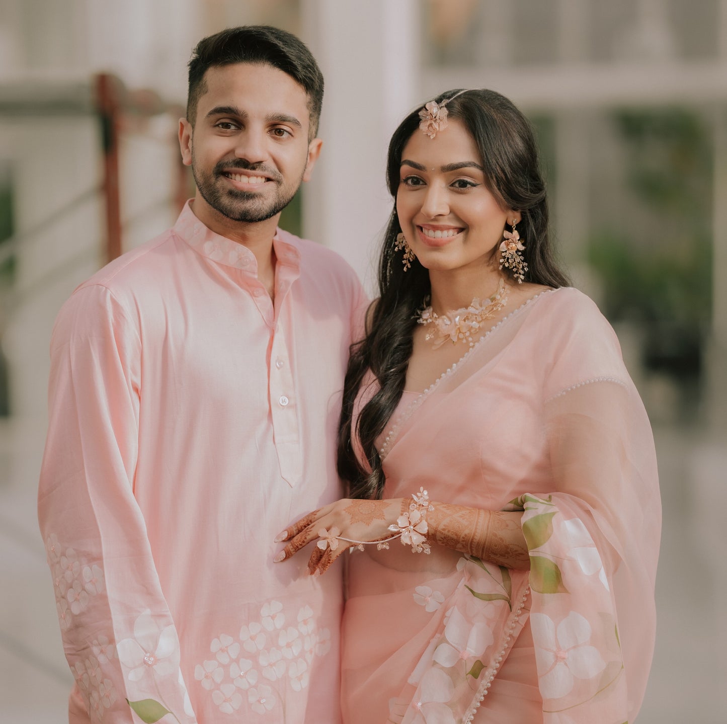 Bride wearing Ellie white resin floral earrings and eos maang tika and hand harness in pink saree with her groom