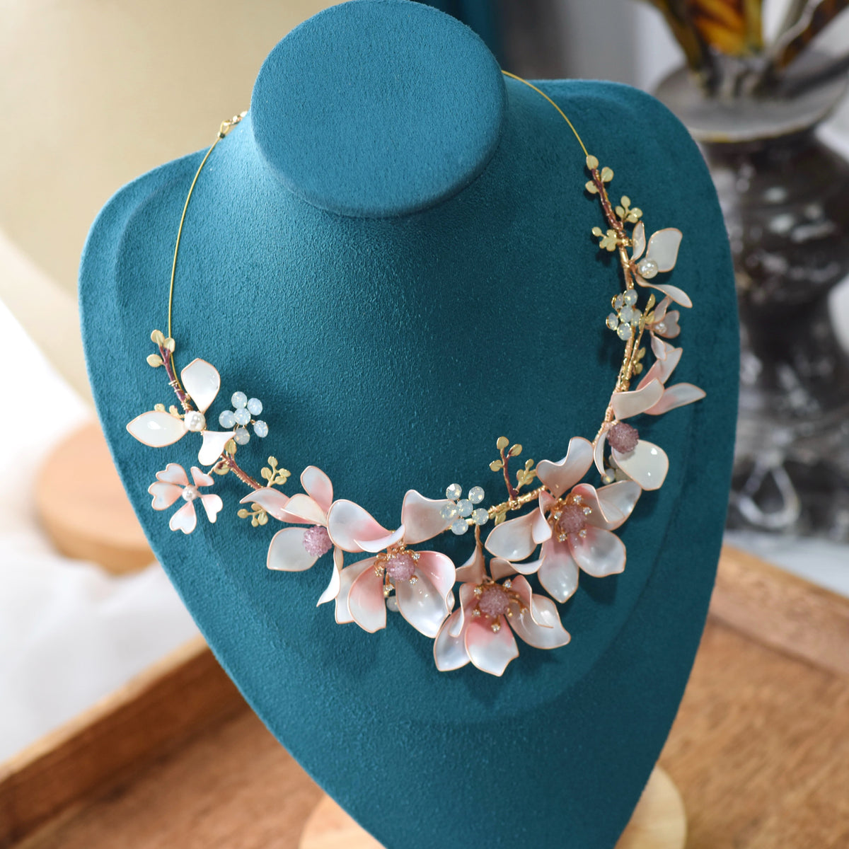 Elvyne white and pink resin floral statement necklace displayed on a stand showing the garland design