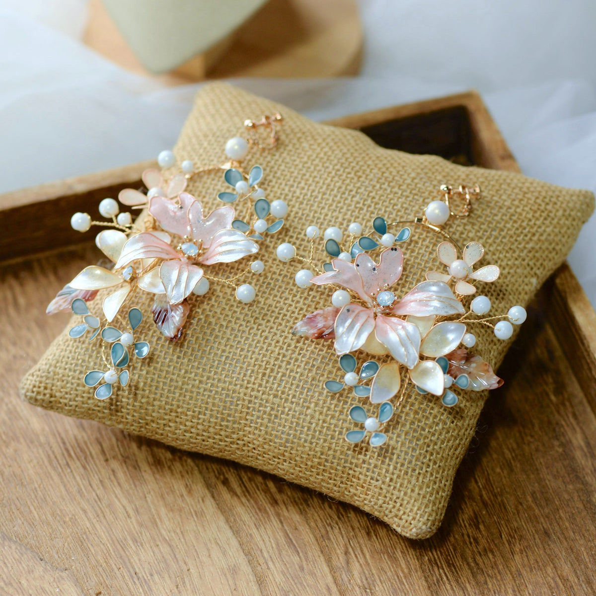 Rivia white pink and pearl resin floral hoop earrings with marbled stone leaves on a jute cushion