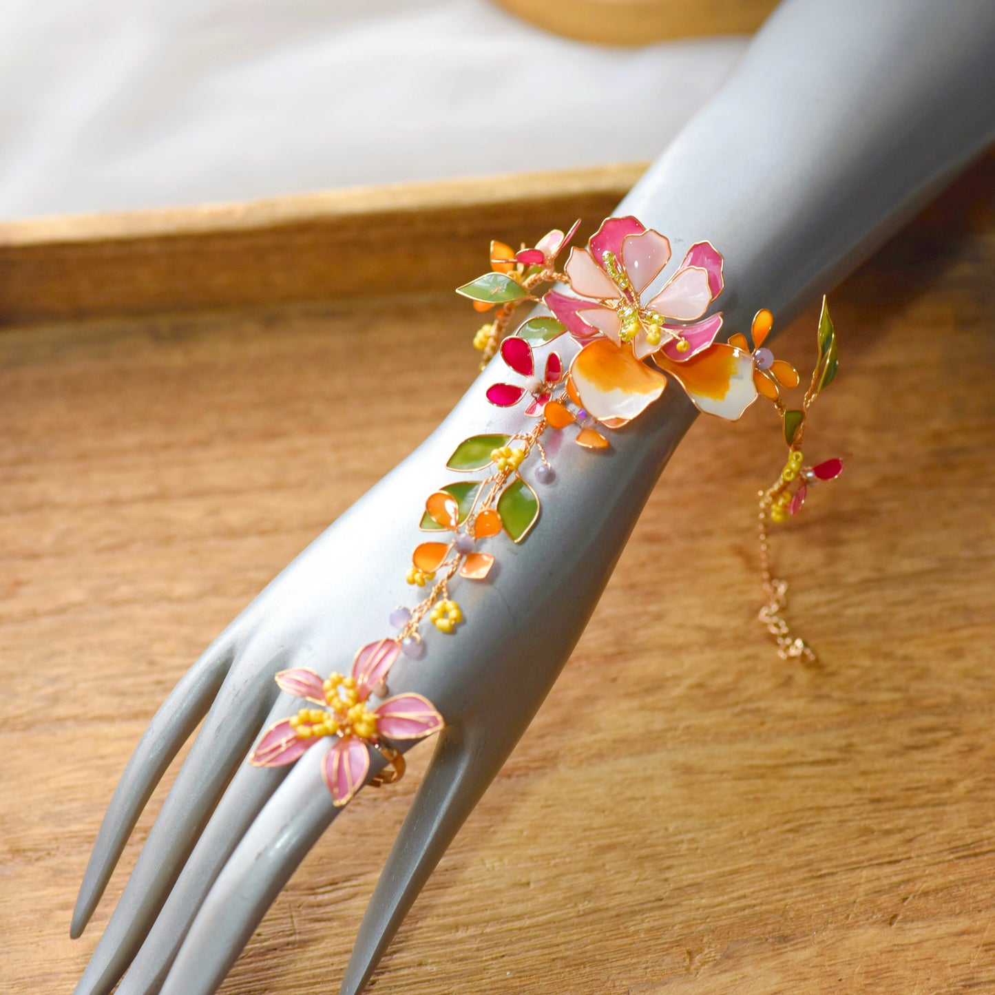 Mannequin wearing Samara haath phool handcrafted resin floral hand harness orange pink gold green