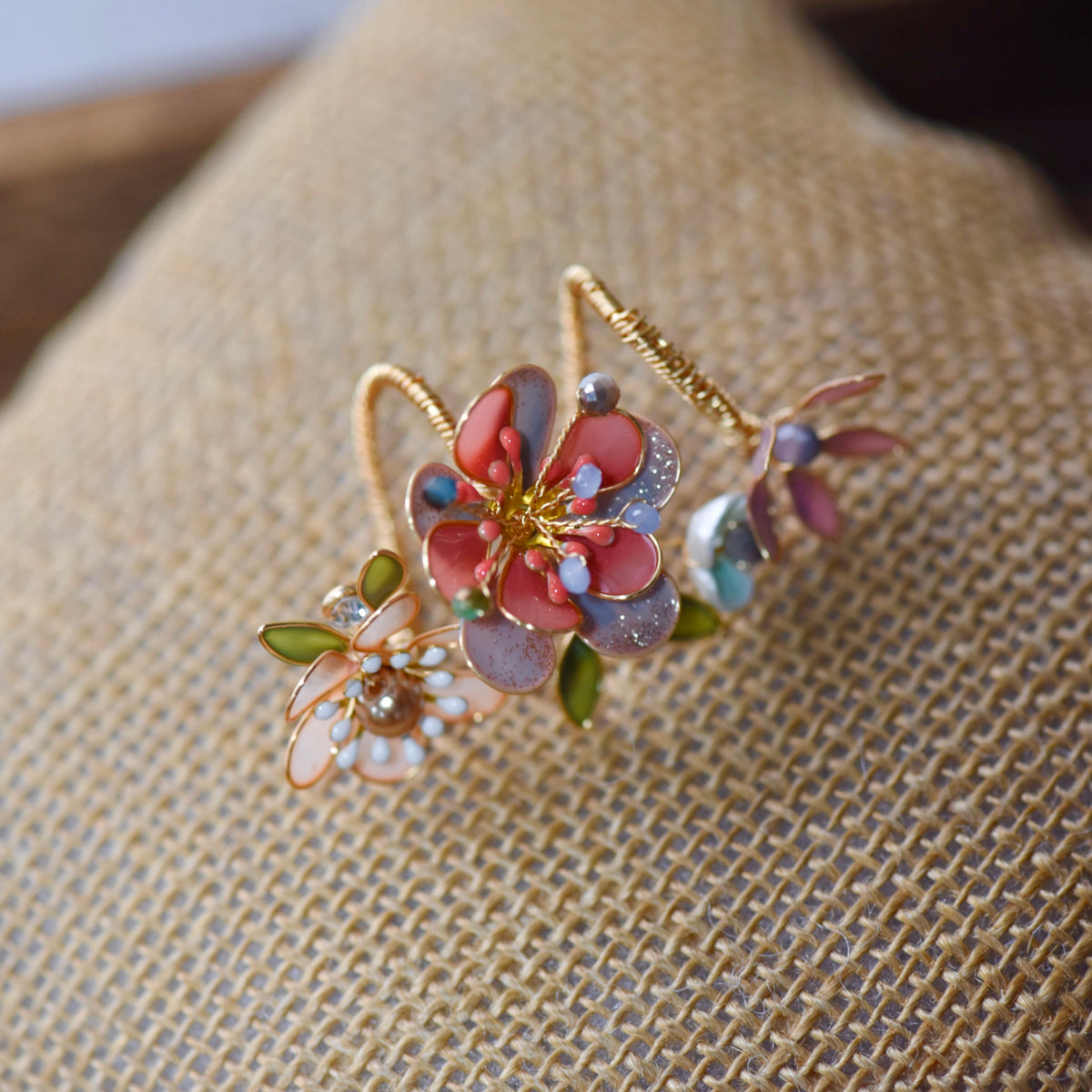 Trina coral resin floral statement ring with pearl centre and green leaves on a jute cushion