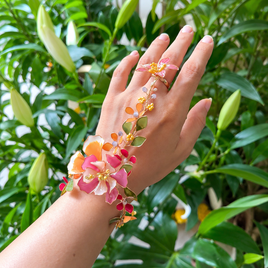 a vibrant rein floral pink and orange haathphool against a rich green forest background