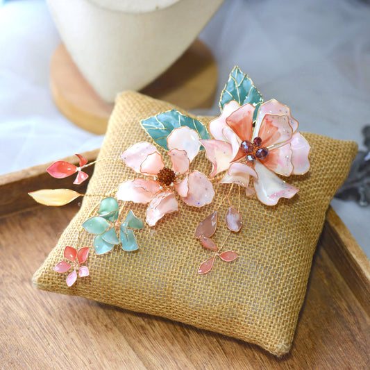 Aeris blush and coral resin floral bridal hair vine with seafoam leaves on jute cushion
