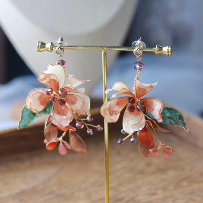 Aeris blush and coral resin floral statement earrings on a display stand showing the cascading silhouette

