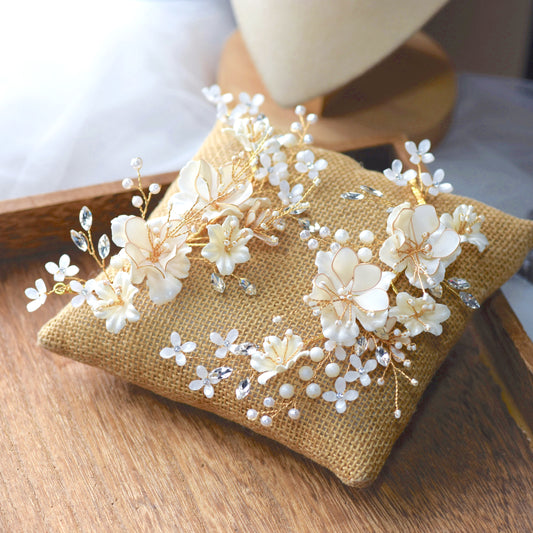 Amara handcrafted white resin floral bridal hair clips set of two gold accents flat lay burlap cushion

