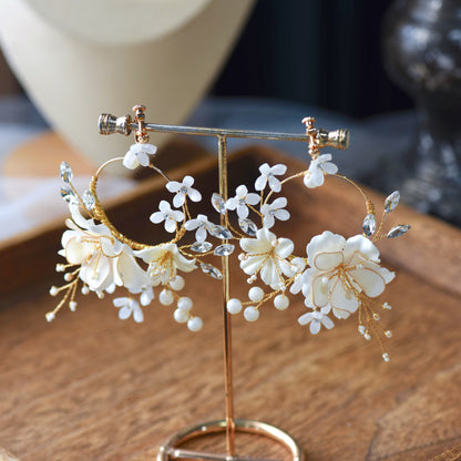 Amara handcrafted white resin floral statement earrings gold accents on stand product shot
