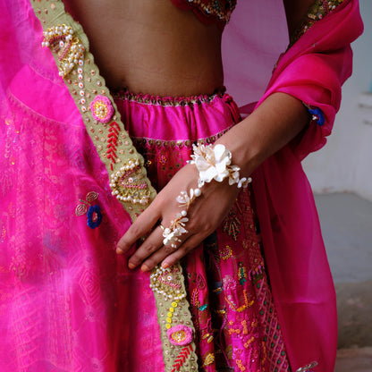 Amara handcrafted white resin floral haath phool hand harness gold accents worn with fuchsia pink lehenga bridal
