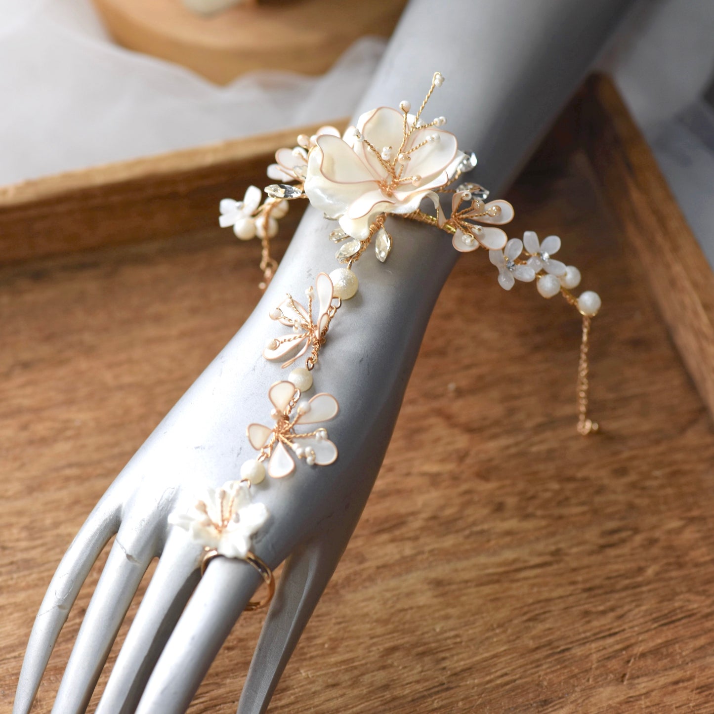 Amara handcrafted white resin floral haath phool hand harness golden accents close-up detail on hand
