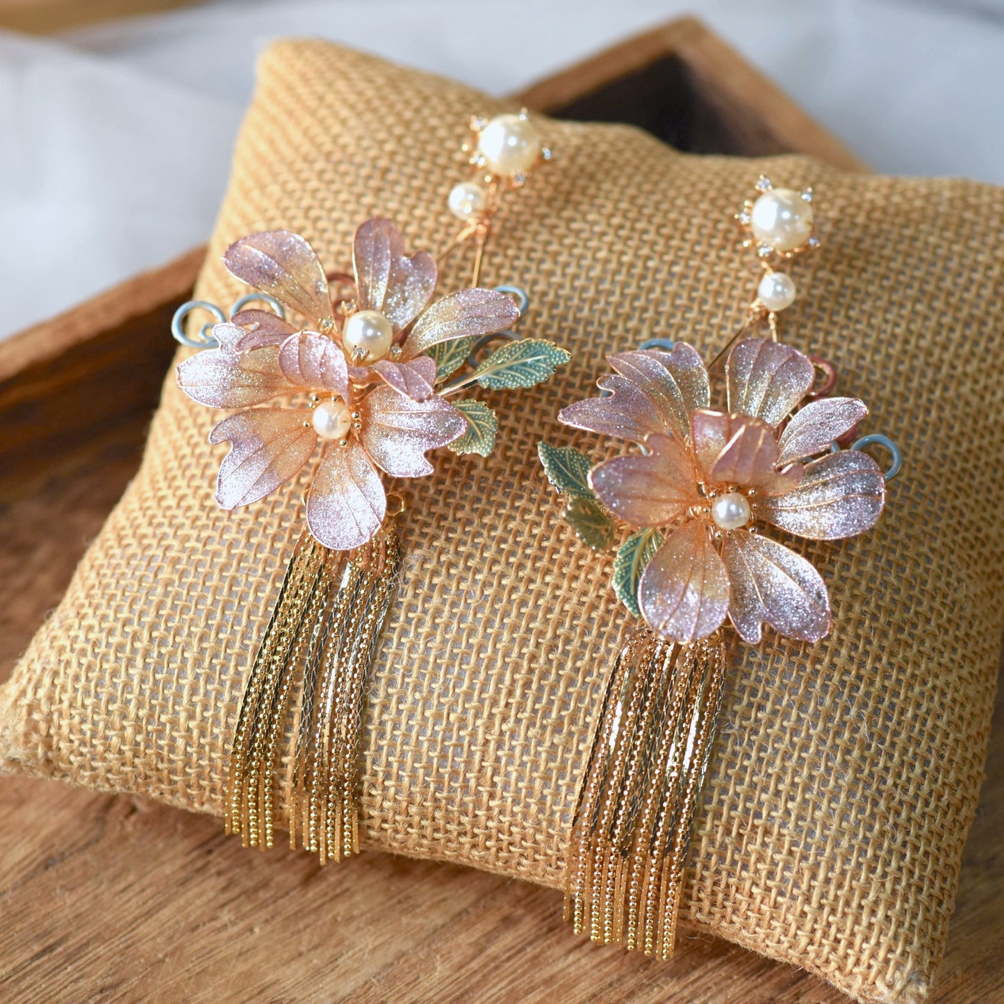 Amaris lavender and mauve resin floral tassel earrings with golden chains shown on a white ear display
