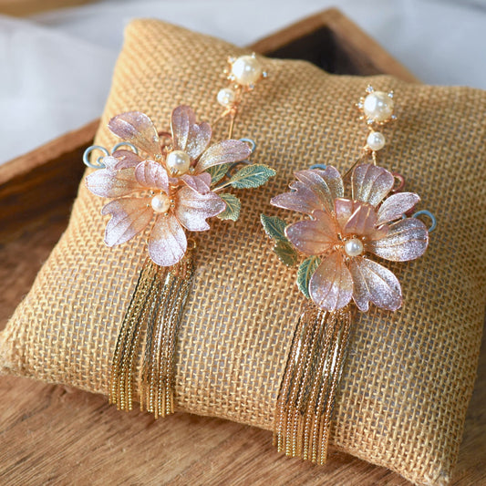 Amaris lavender and mauve resin floral tassel earrings with golden chains shown on a white ear display
