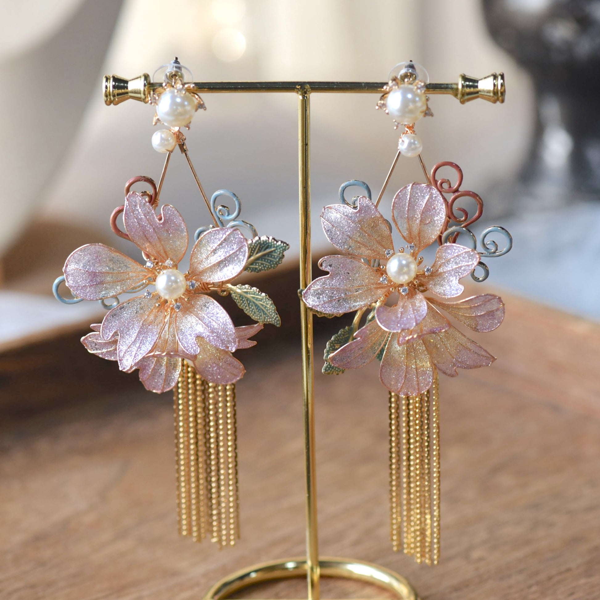 Amaris lavender resin floral earring detail showing pearl centre green metal leaves and gold tassel
