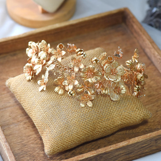 Andromeda gold floral bridal crown with sculpted metallic petals on jute cushion
