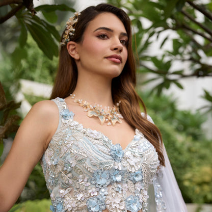 Model wearing Angelica blush and blue resin floral butterfly necklace in ivory lehenga
