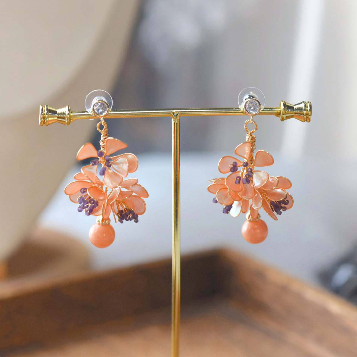 Apricot Fleur apricot-orange resin floral earrings on display stand
