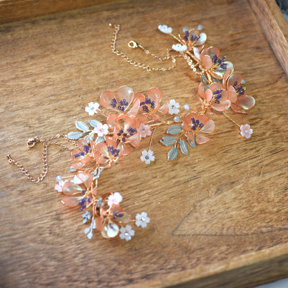 Apricot Fleur long hand harness with apricot, lilac and ivory resin flowers on gold wire, laid flat on a wooden tray
