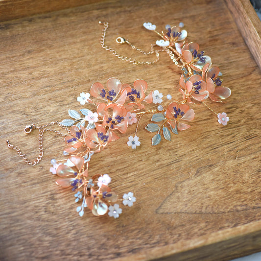 Apricot Fleur long hand harness with apricot, lilac and ivory resin flowers on gold wire, laid flat on a wooden tray
