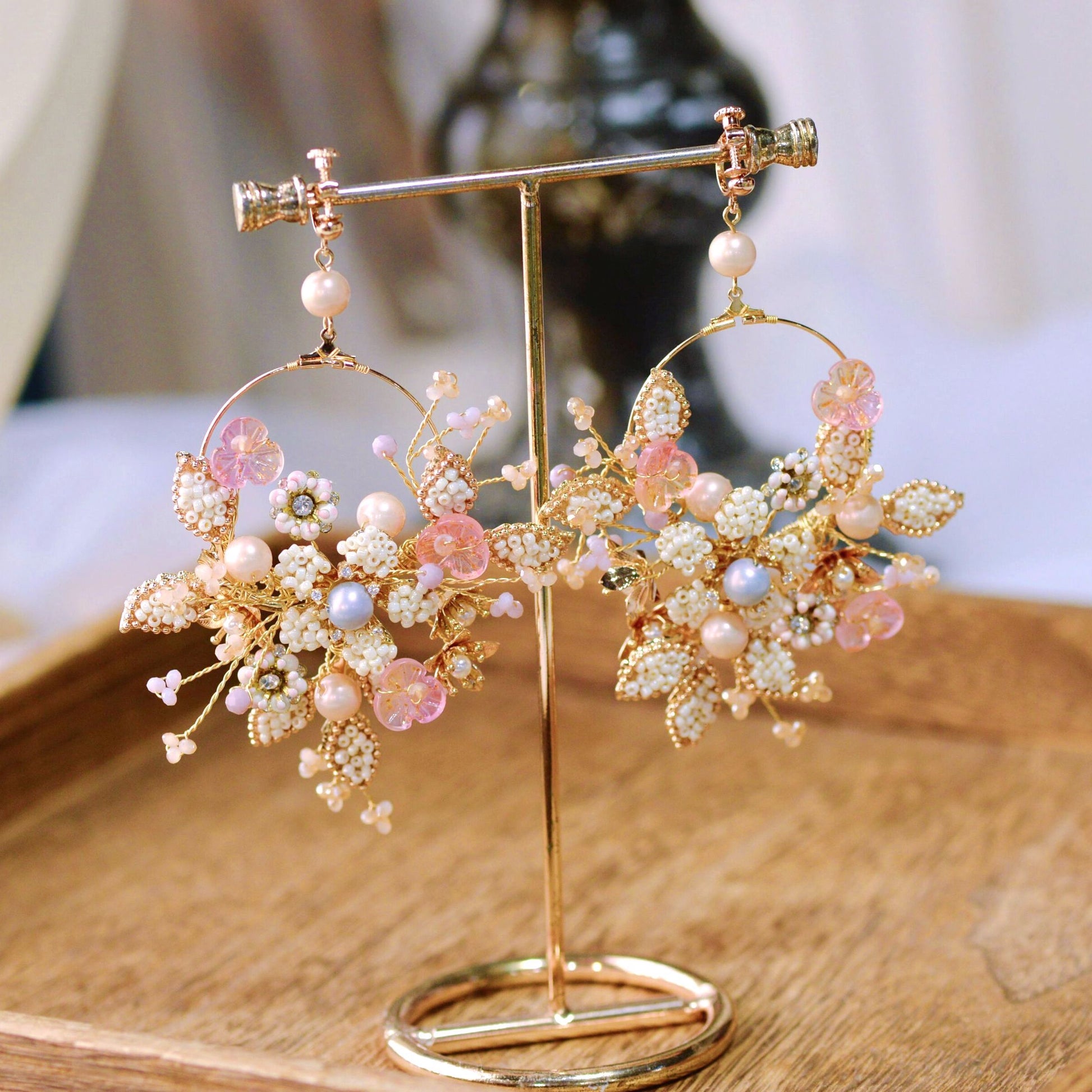 Arabella handcrafted metal bead floral hoop earrings golden cream blush pink pearl on gold stand close-up
