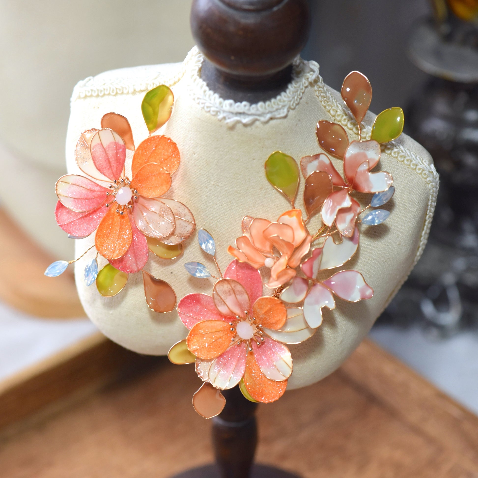Side view of Arancia floral hair accessory showcasing layered resin petals, translucent leaves and gold wirework