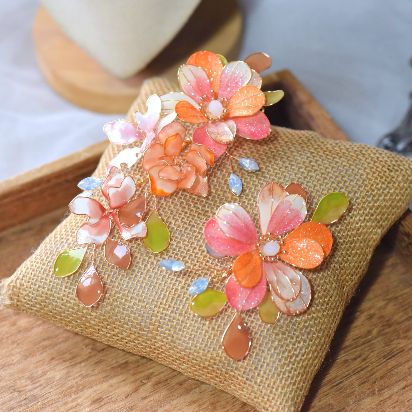 Arancia handcrafted floral hair accessory featuring coral and orange resin flowers with pastel leaves and gold detailing