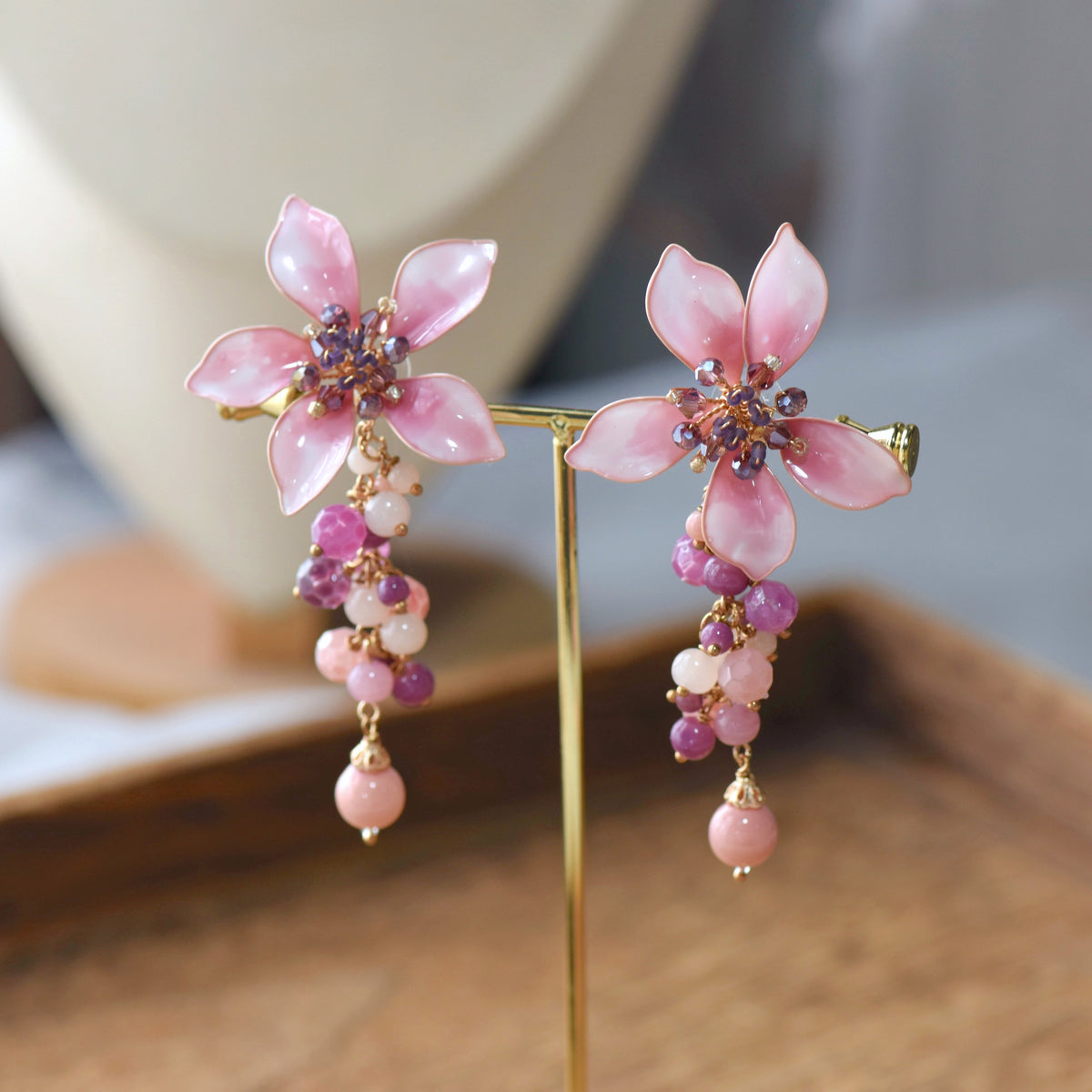 Aurelia blush pink and lilac resin floral drop earrings on a display stand
