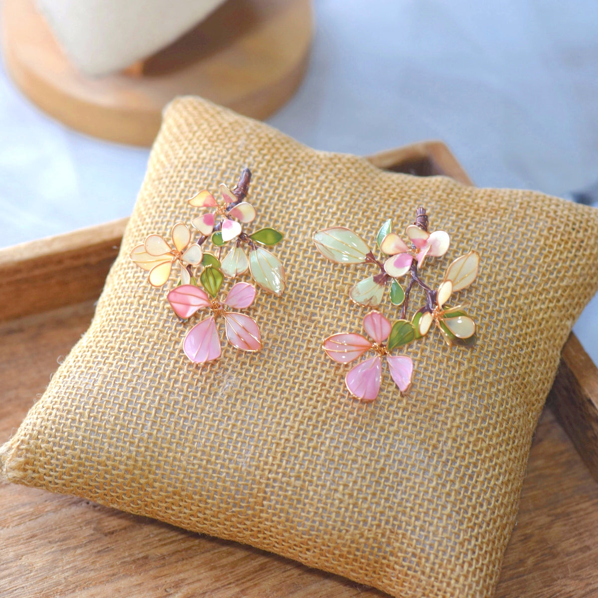 Aveline blush pink green and pearl white resin floral earrings on a jute cushion
