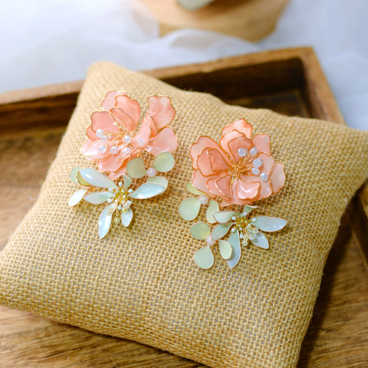 Ayaka peach and mint resin floral statement earrings on a jute cushion
