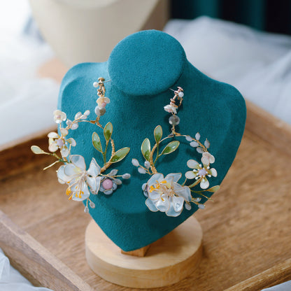 Bluesette handcrafted blue green resin floral drop earrings on teal bust close-up detail
