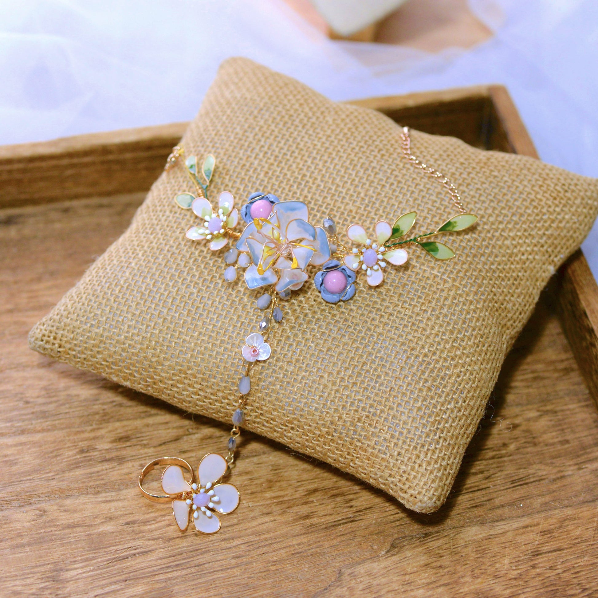 Bluesette handcrafted blue green white gold resin floral haath phool hand harness flat lay burlap cushion
