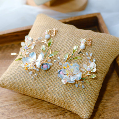 Bluesette handcrafted blue green white resin floral drop earrings flat lay burlap cushion botanical statement
