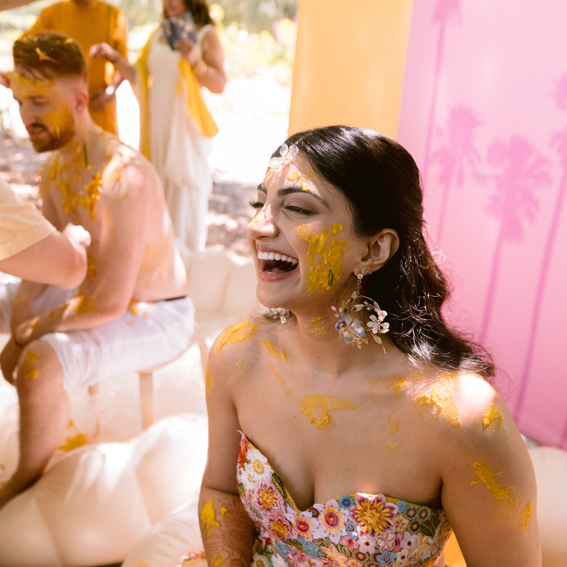 Bride wearing Bluesette handcrafted blue green resin floral drop earrings at haldi ceremony laughing joyful
