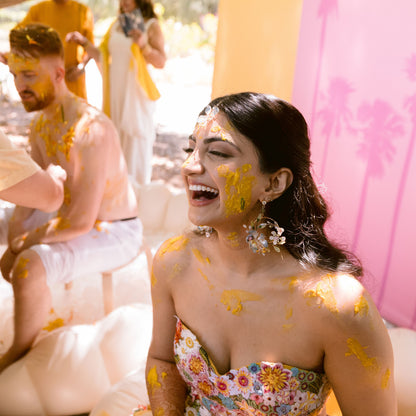 Bride wearing Bluesette handcrafted blue green resin floral drop earrings at haldi ceremony laughing joyful
