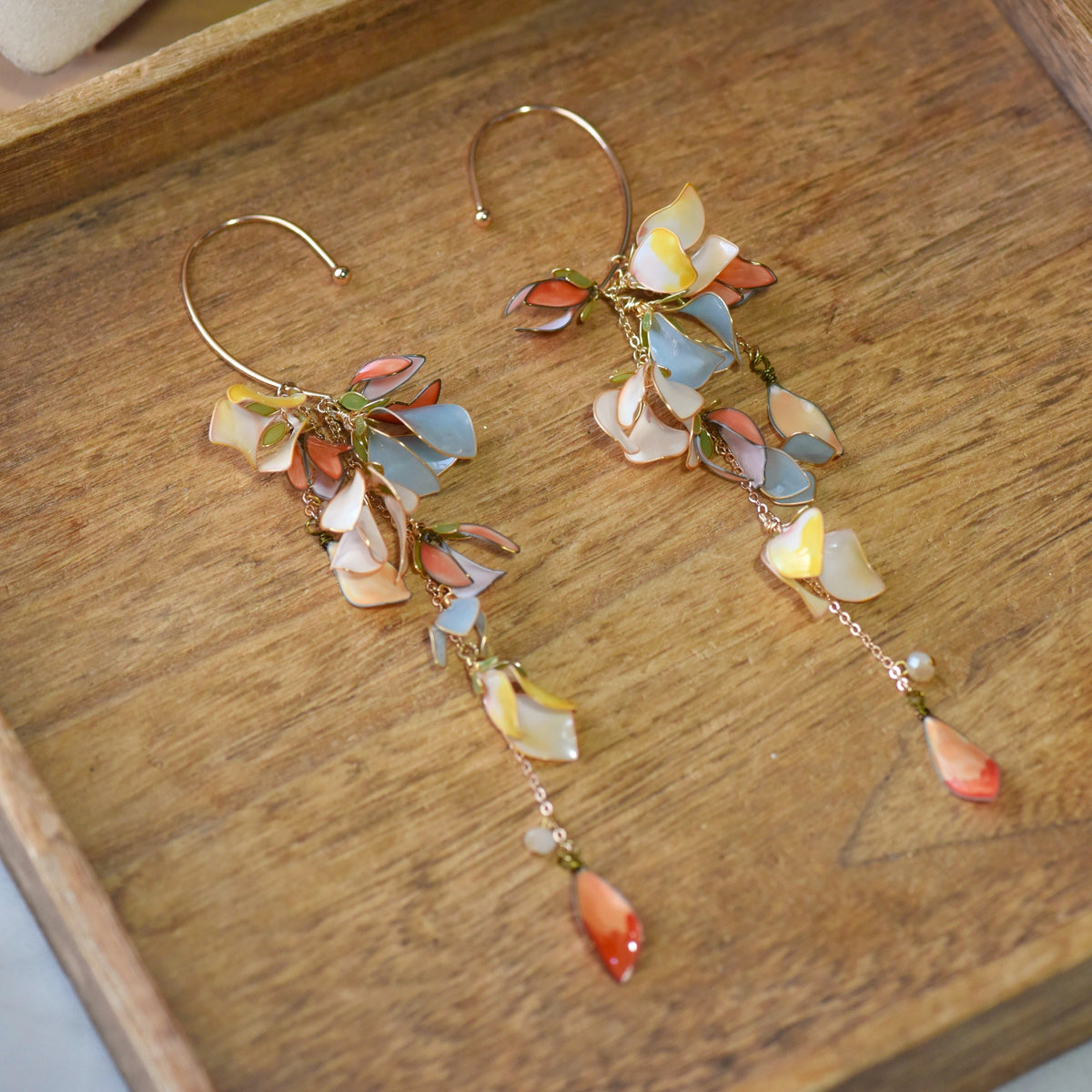 Brielle sky blue and coral resin floral ear cuffs pair laid on a wooden surface
