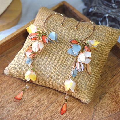 Brielle yellow blue and peach resin floral cascading ear cuffs on a jute cushion
