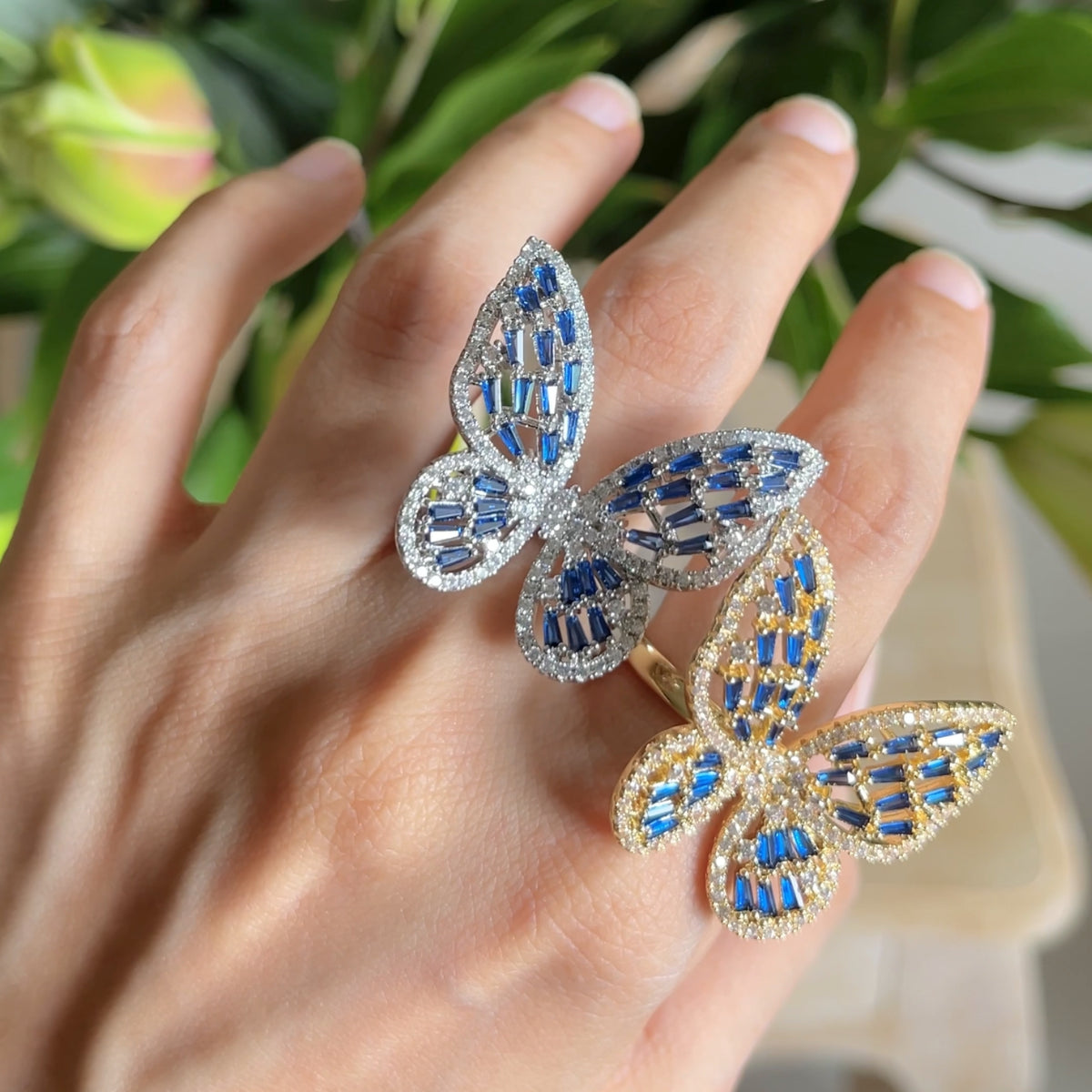 Butterfly Ring II zirconia butterfly ring in golden and blue and  silver and blue on hand, worn.
