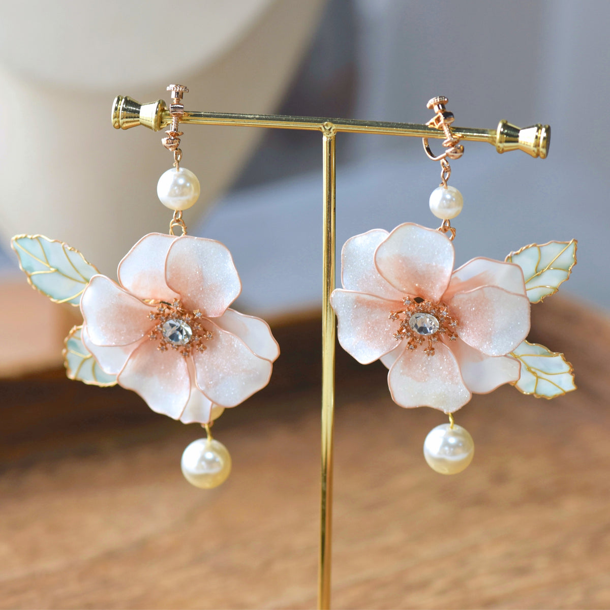 Camellias white resin floral drop earrings with pearl drops on a display stand
