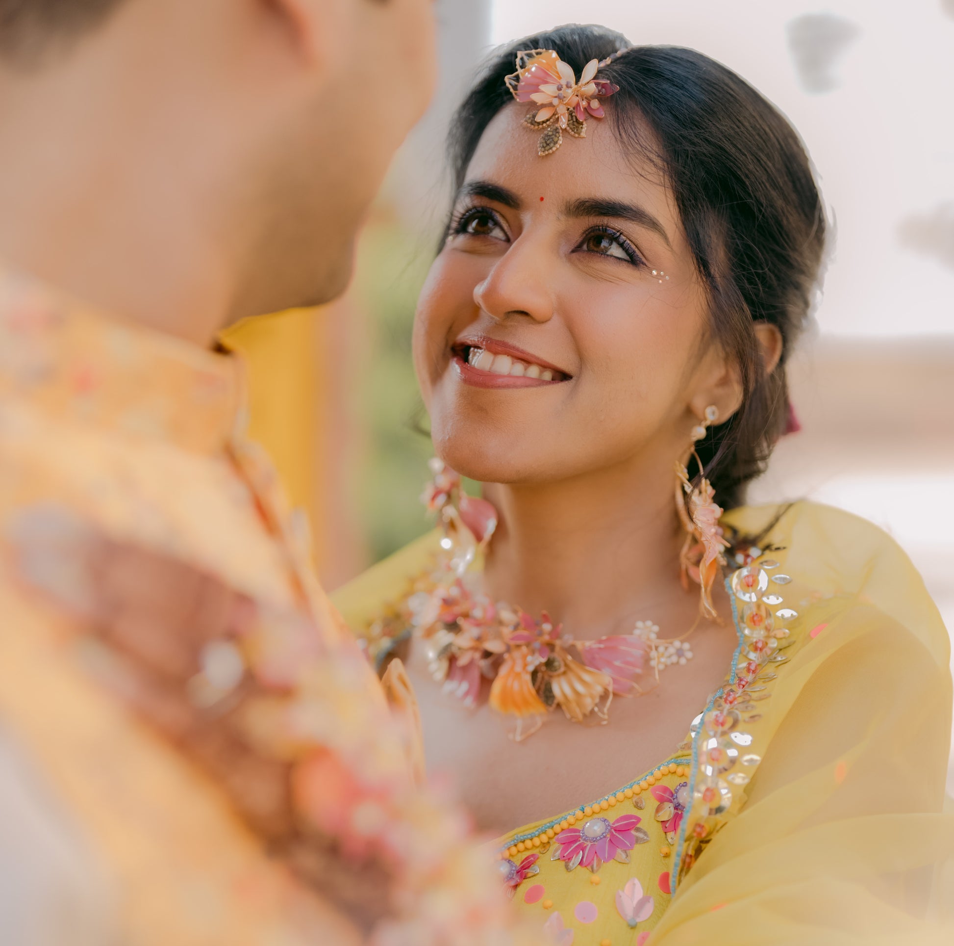 Bride wearing Catriona handcrafted resin floral necklace earrings and maang tika pink orange gold haldi yellow lehenga
