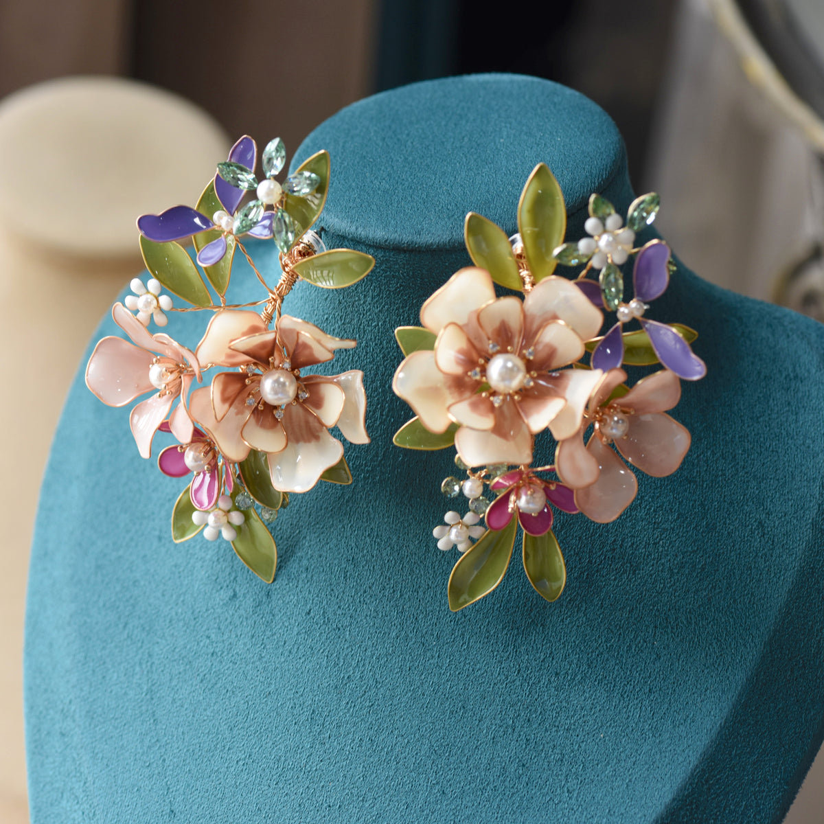 Chloe blush and mauve resin floral statement earrings displayed on a stand
