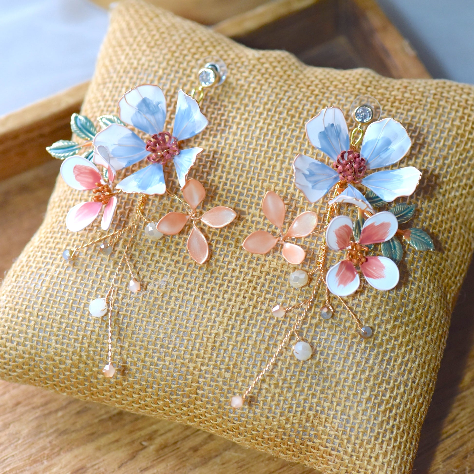 Close up of Clara floral earrings with pastel blue and pink resin petals