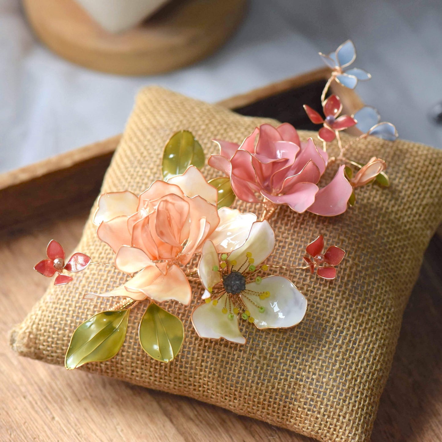 Cora handcrafted resin floral bridal hair accessory close-up blush pink peach coral green gold wirework detail
