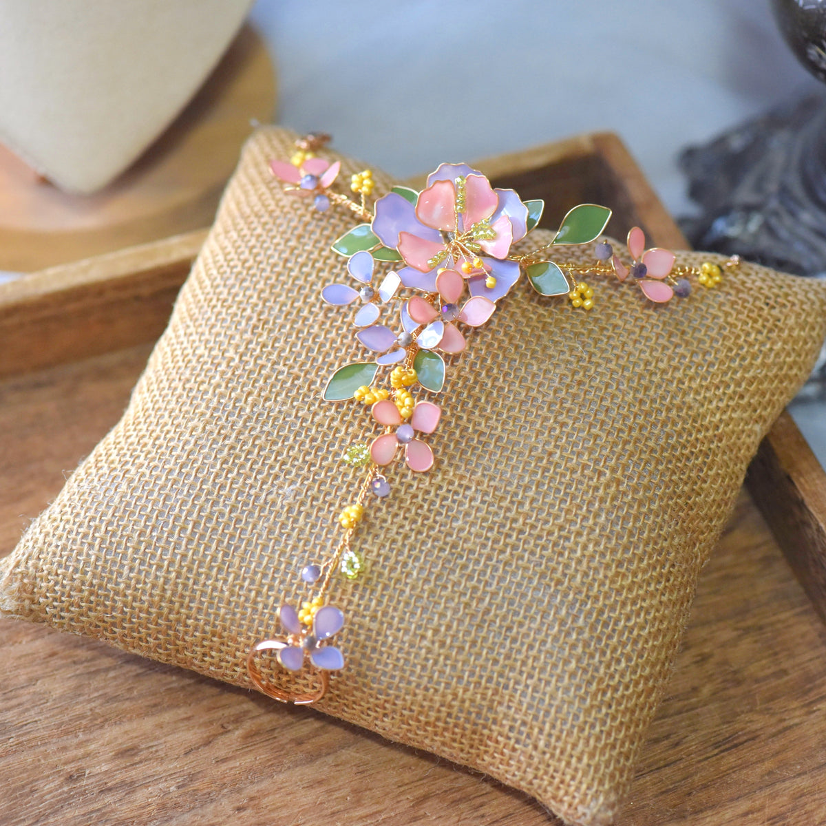 Ella blush pink and lavender resin floral haath phool with sage leaves on a jute cushion