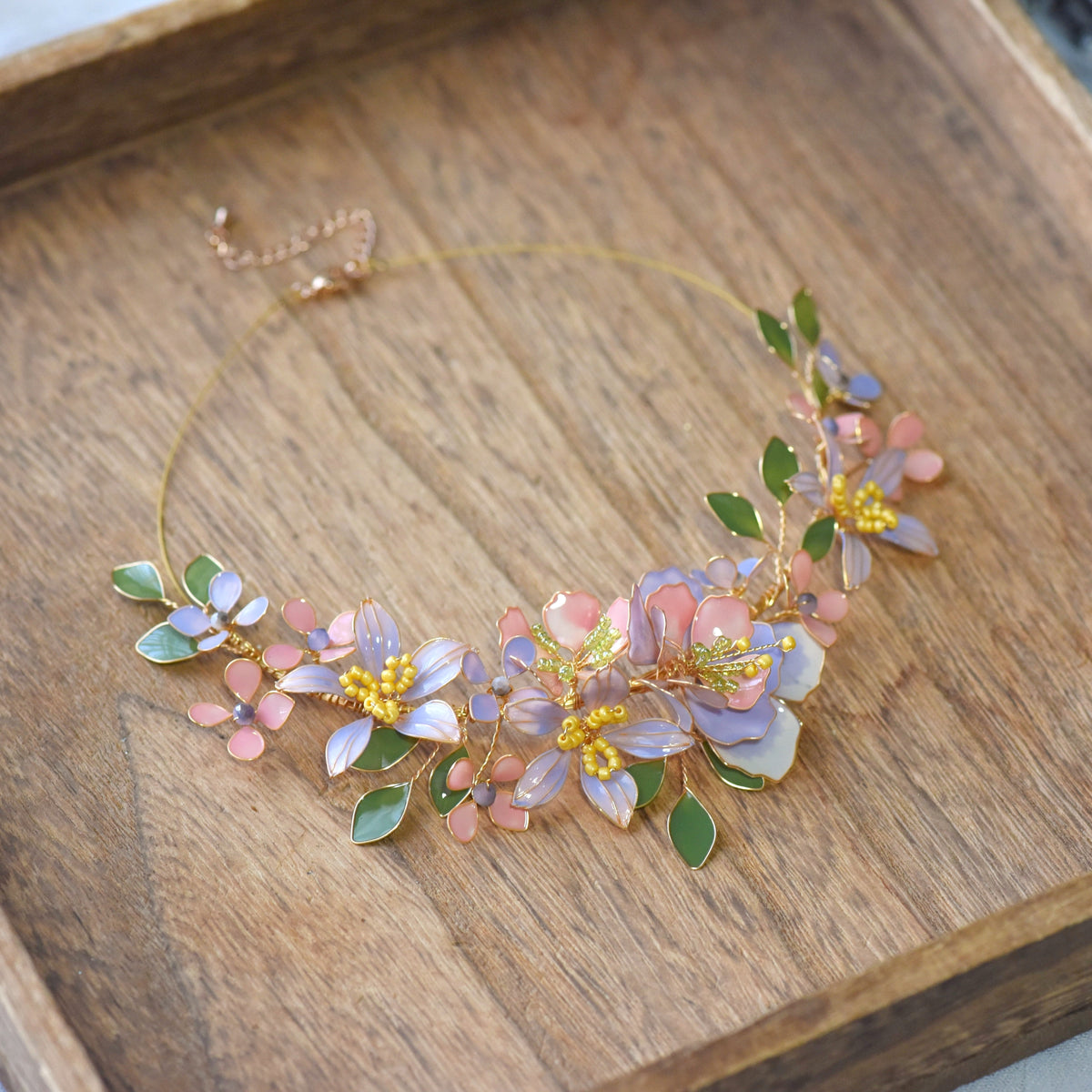 Ella blush pink and lavender resin floral garland necklace with sage leaves on a wooden surface
