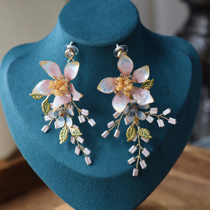 Ellie white and ivory resin floral earrings with golden wirework on blue bust
