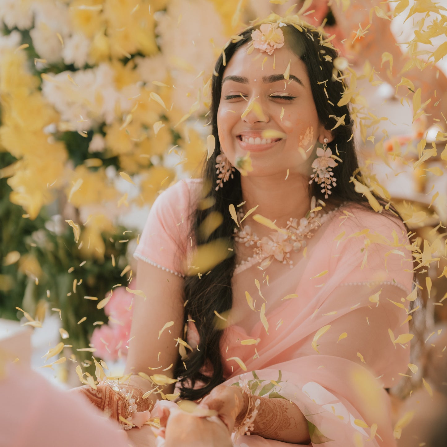 Bride Menaka wearing Ellie white and gold resin floral earrings at her haldi ceremony with eos maang tika and haath phools
