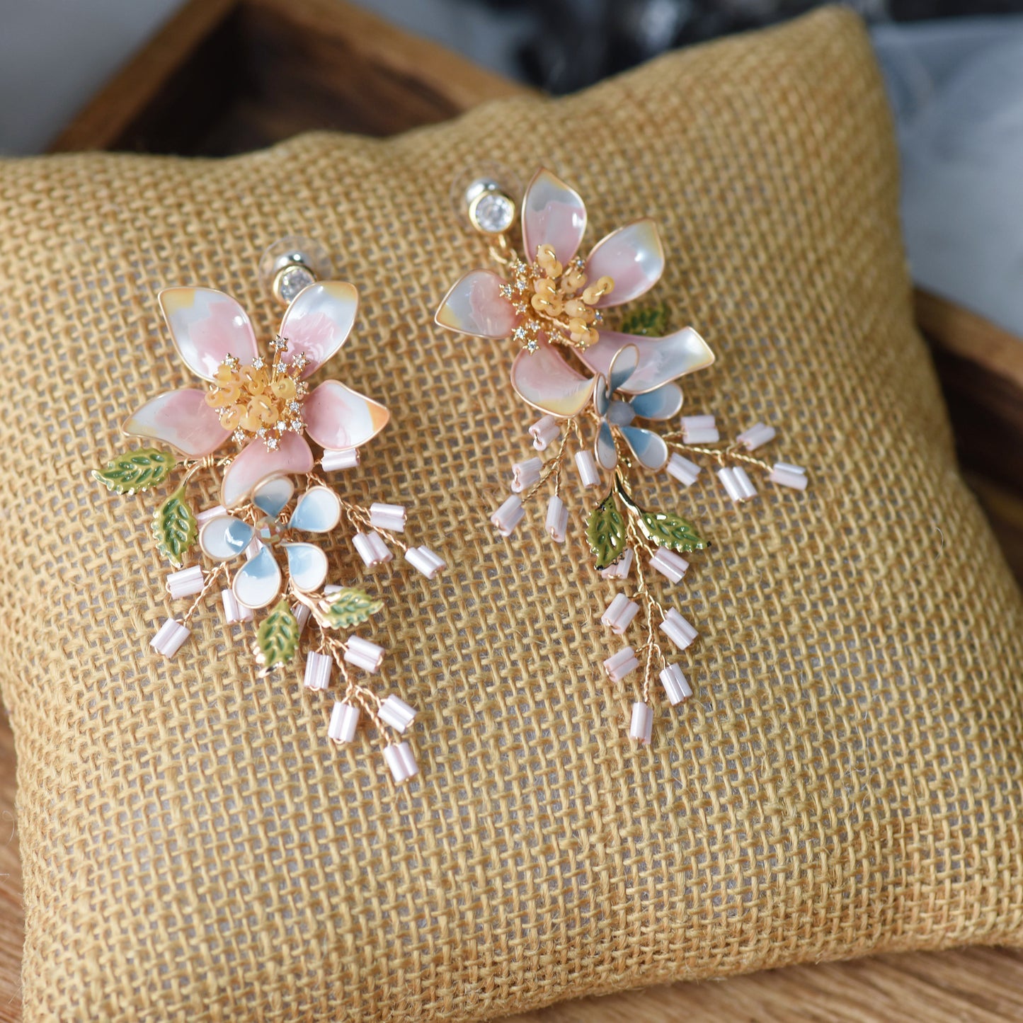 Ellie white and gold resin floral earrings with cascading detail on jute cushion
