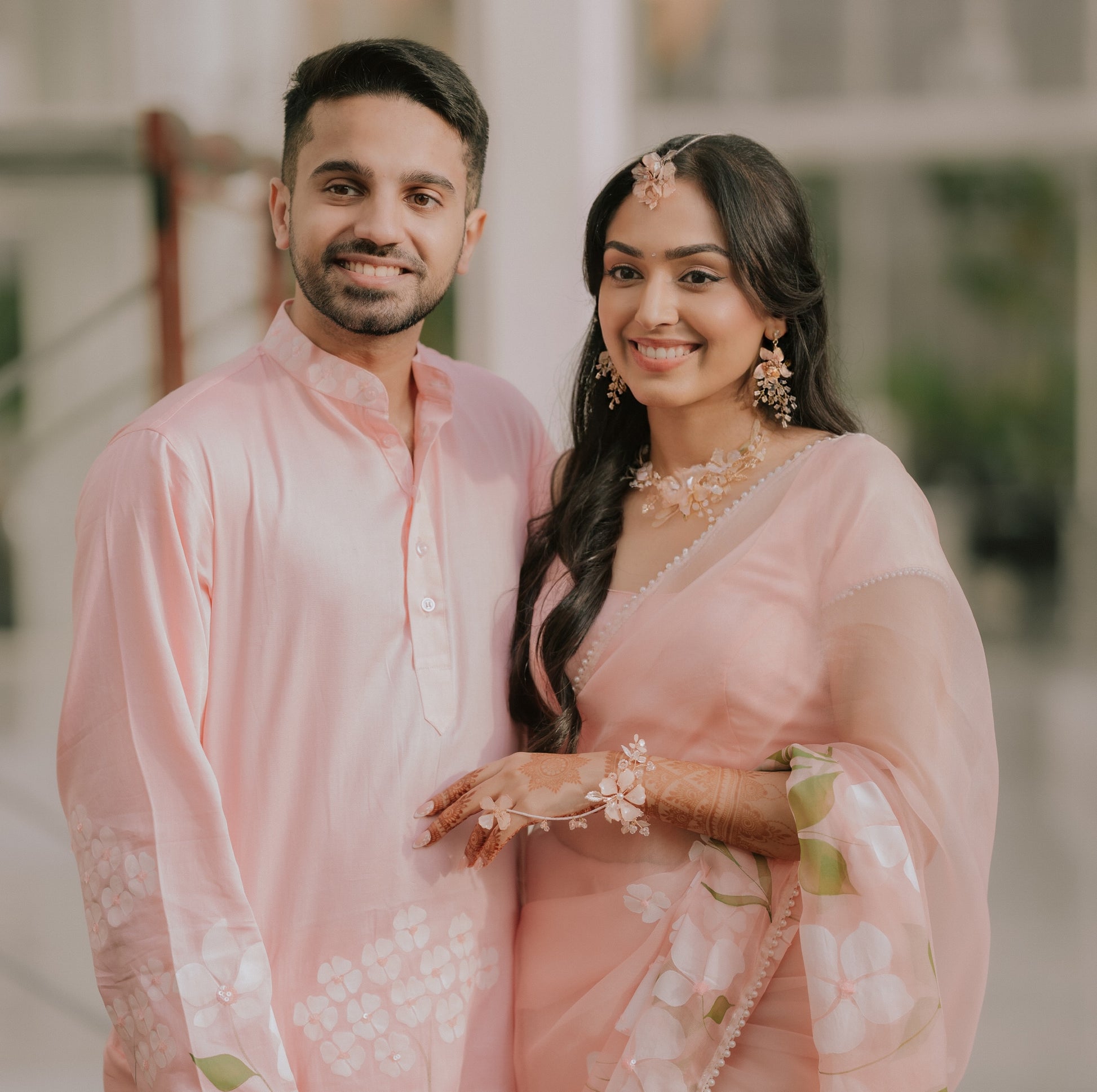 Bride wearing Ellie white resin floral earrings and eos maang tika and hand harness in pink saree with her groom
