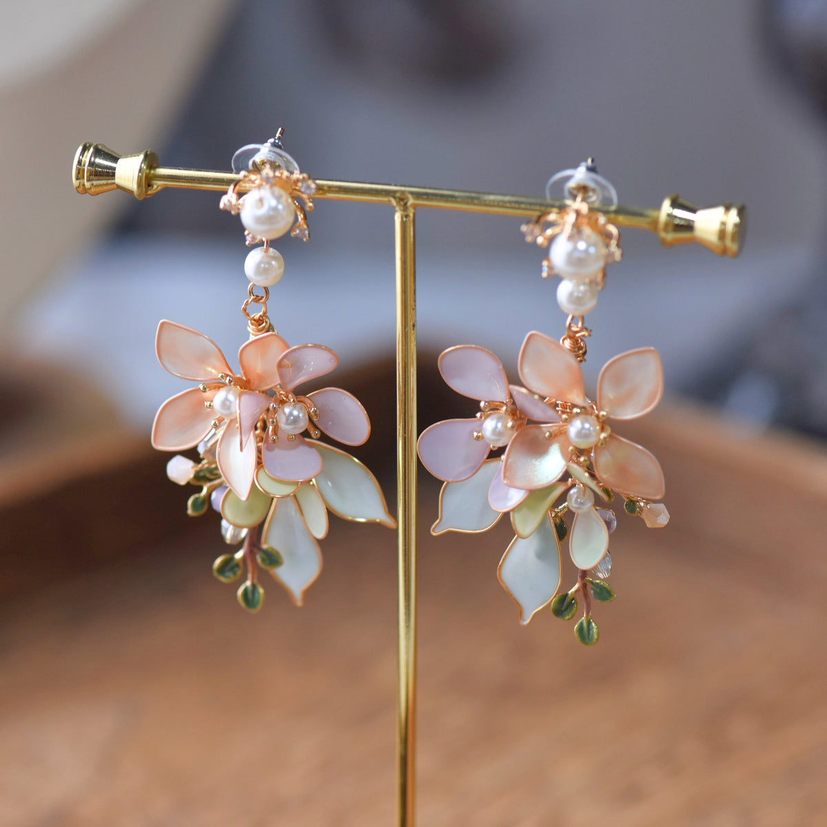 Elowen blush and mint resin floral statement earrings on a display stand showing layered petals
