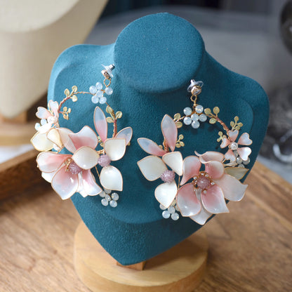 Elvyne white and pink resin floral statement earrings displayed on a stand
