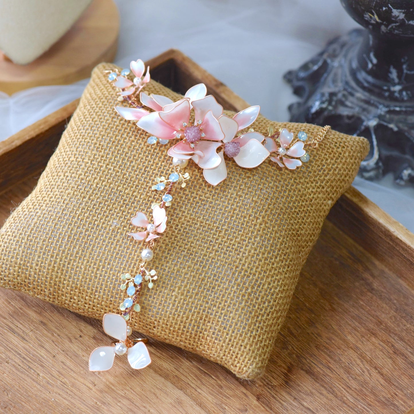 Elvyne white resin floral hand harness with soft pink centres laid on a jute cushion
